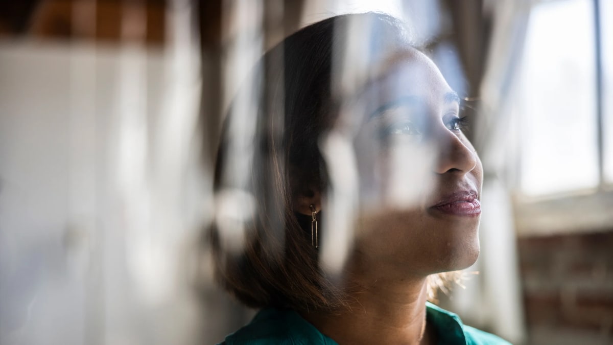 Professional woman confidently stepping forward through an open door toward new opportunities