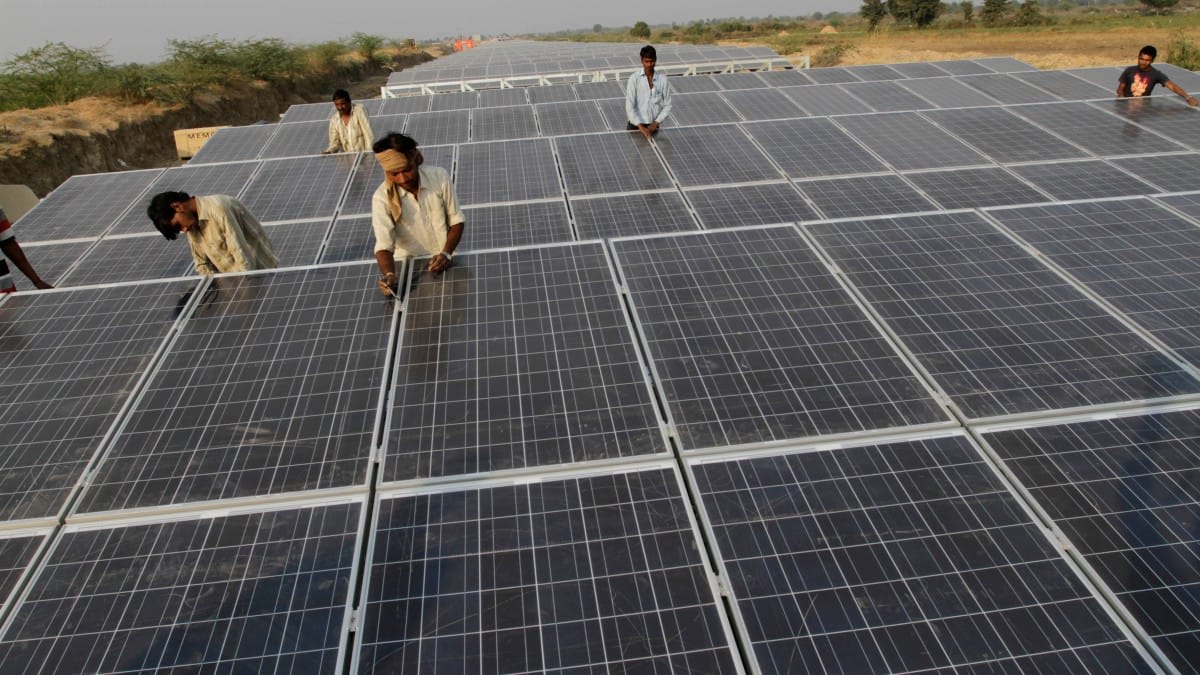 Solar panels gleaming under bright sun with power transmission lines in background
