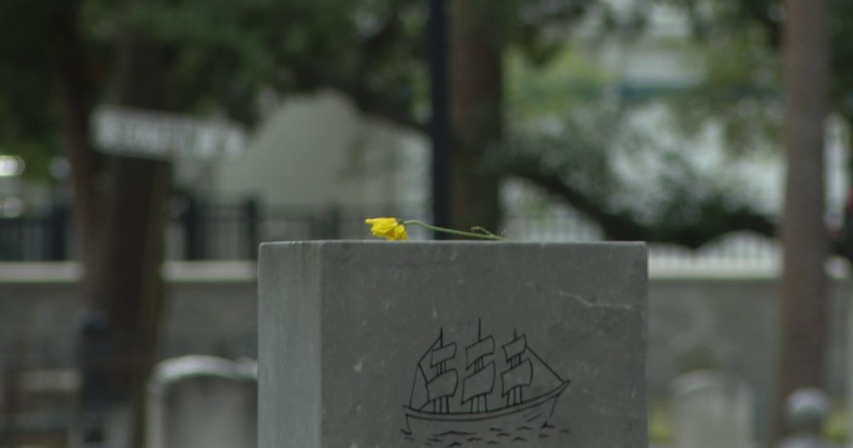 Volunteers placing American flags on historic gravestones at Tampa's Oaklawn Cemetery