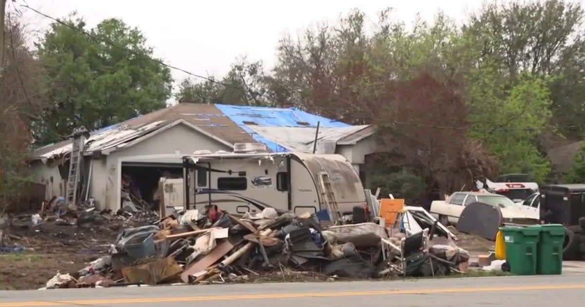 Volunteers operating bobcat machinery cleaning debris from overgrown Florida residential property