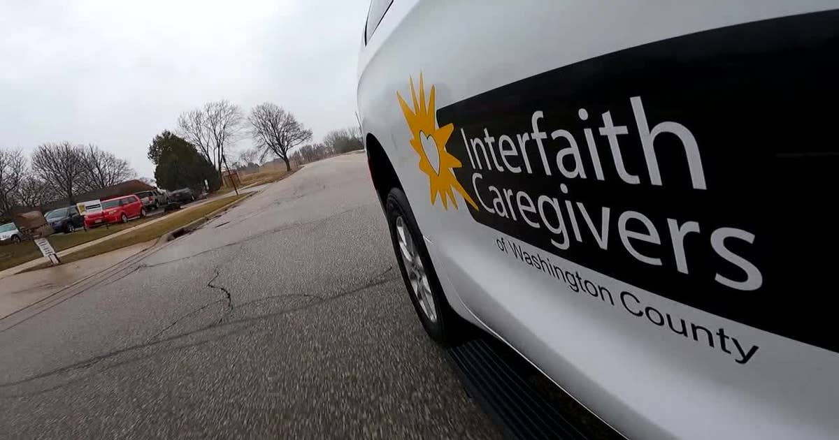 Senior volunteer driver helping elderly passenger into car for medical appointment in Wisconsin