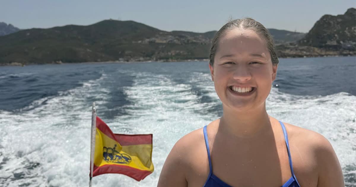 Young woman swimmer Maya Merhige in open water wearing goggles and swim cap with handwritten names
