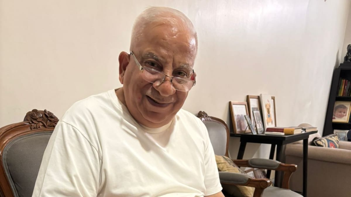 Elderly Indian man reviewing banking documents at desk with hopeful expression