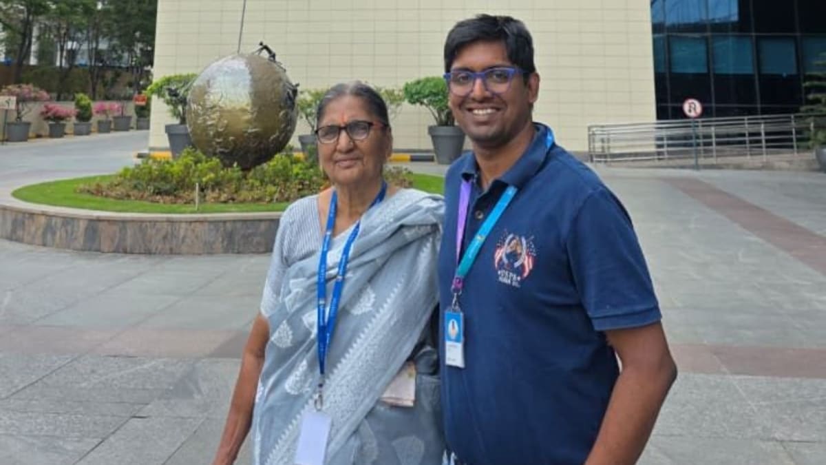 ** Elderly Indian woman standing with her grandson inside modern Microsoft office campus building