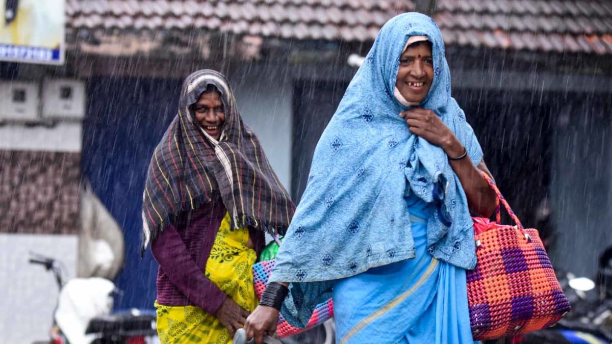 ** Commuters walking through monsoon rains on waterlogged streets in Bengaluru, Karnataka, India