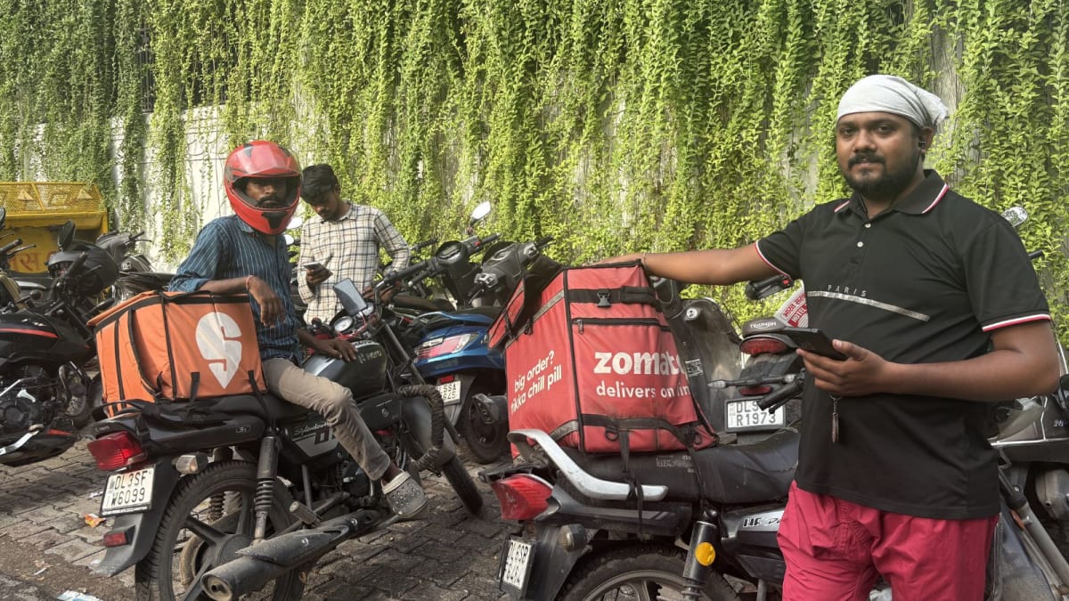 Food delivery driver on electric bike in Mumbai traffic wearing safety gear and helmet