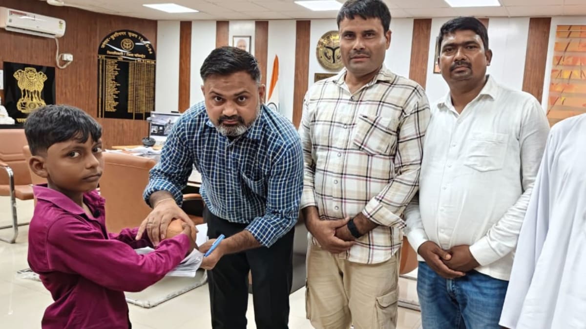 Young Indian boy in school uniform handing clay piggy bank to district official