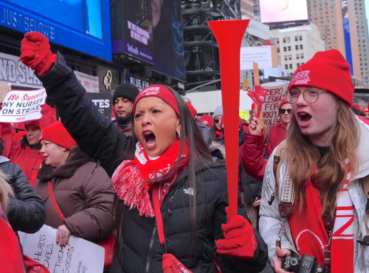 New York City nurses in red union gear marching on picket line during historic healthcare strike