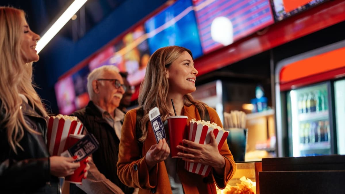 Diverse group of people standing in line at modern movie theater entrance