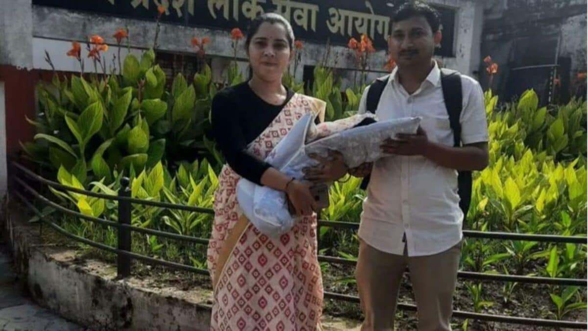 ** Varsha Patel in police uniform standing with her husband and infant daughter