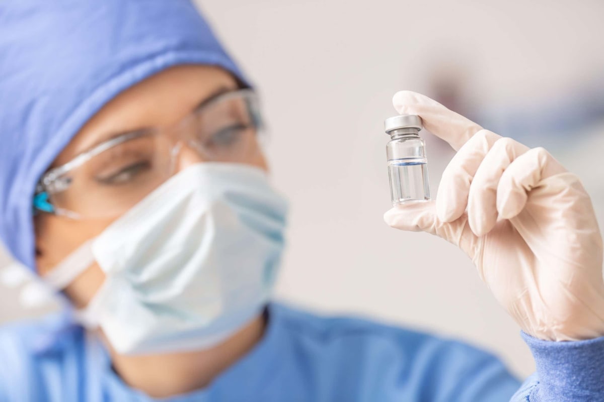 Medical researcher holding vial of mRNA vaccine in modern laboratory setting