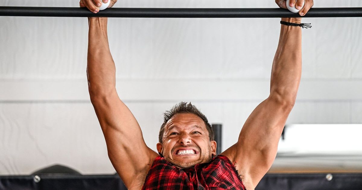 Lance Pecht performing grappler pullups gripping lacrosse balls over gym bar