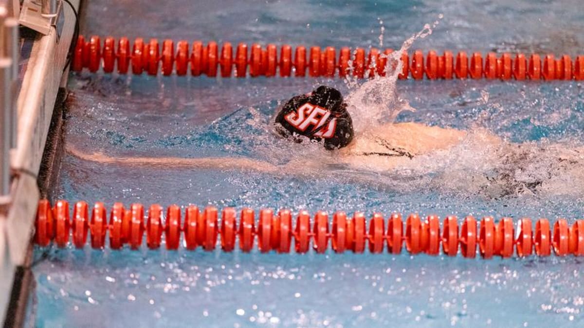 College swimmers celebrating academic achievement with caps and gowns near swimming pool