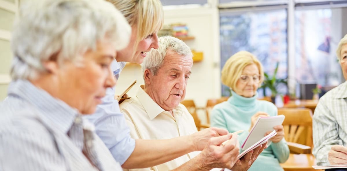Caregiver smiling with elderly dementia patient during therapeutic music session in memory care facility