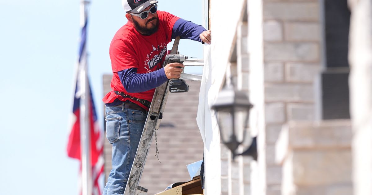 Construction worker installing window frame on new residential home under sunny skies