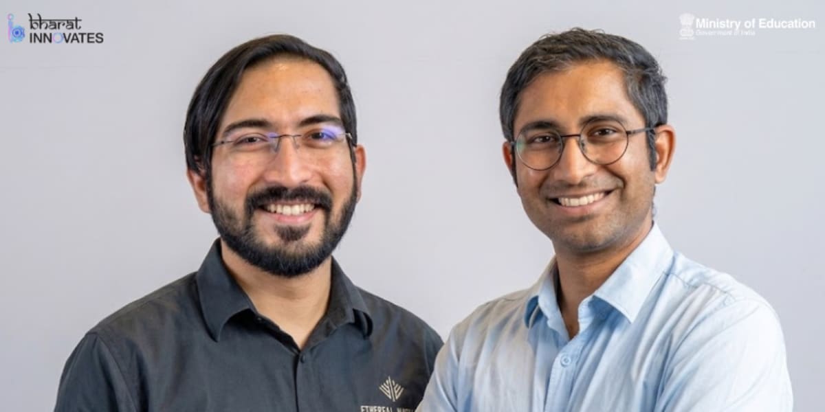 Two young Indian engineers standing beside precision manufacturing equipment in modern factory facility