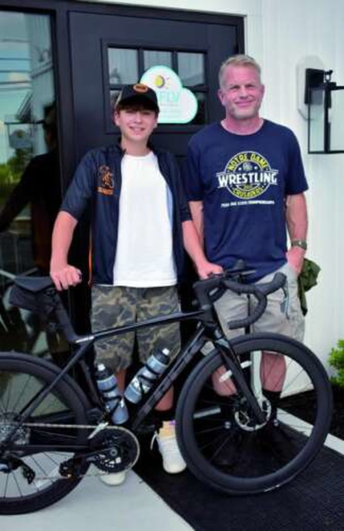 Teen cancer survivor Carter Boyle smiles with new Trek road bike surrounded by family and union workers