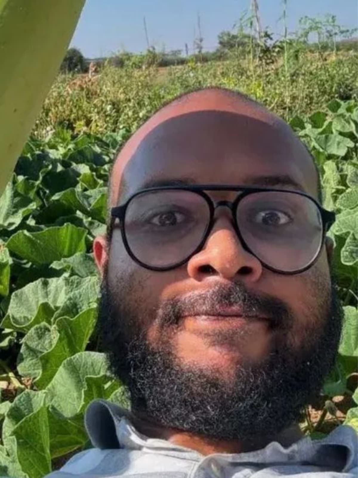 Young farmer Abhishek Reddy standing among fruit trees and crops on his sustainable permaculture farm