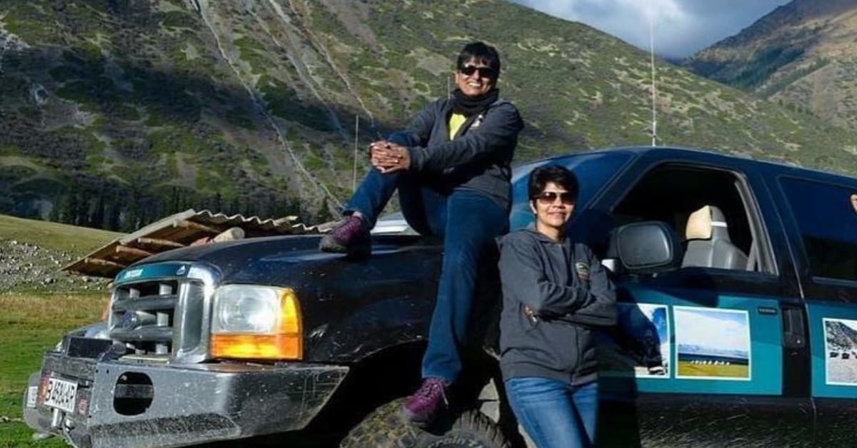 Two Indian women standing beside cars during an international self-drive expedition