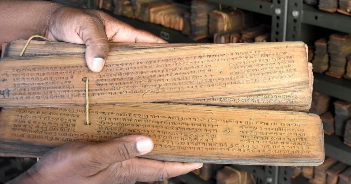Ancient palm leaf manuscript with carved Sanskrit text in climate controlled archive room