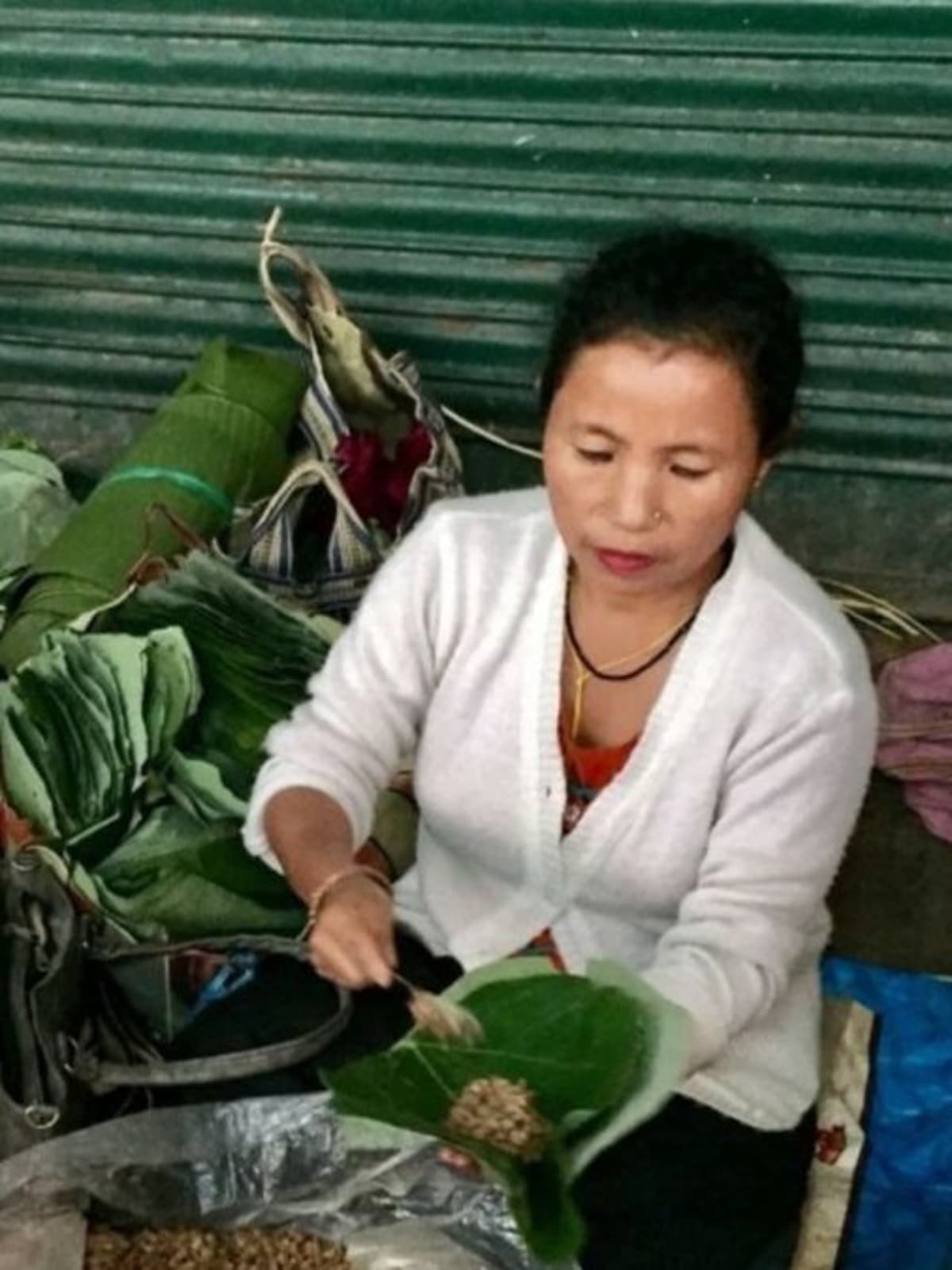 Indian shopkeeper handing customer reusable cloth bag in colorful outdoor market