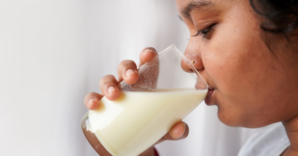 Mother opening carton of shelf-stable milk for child during train journey