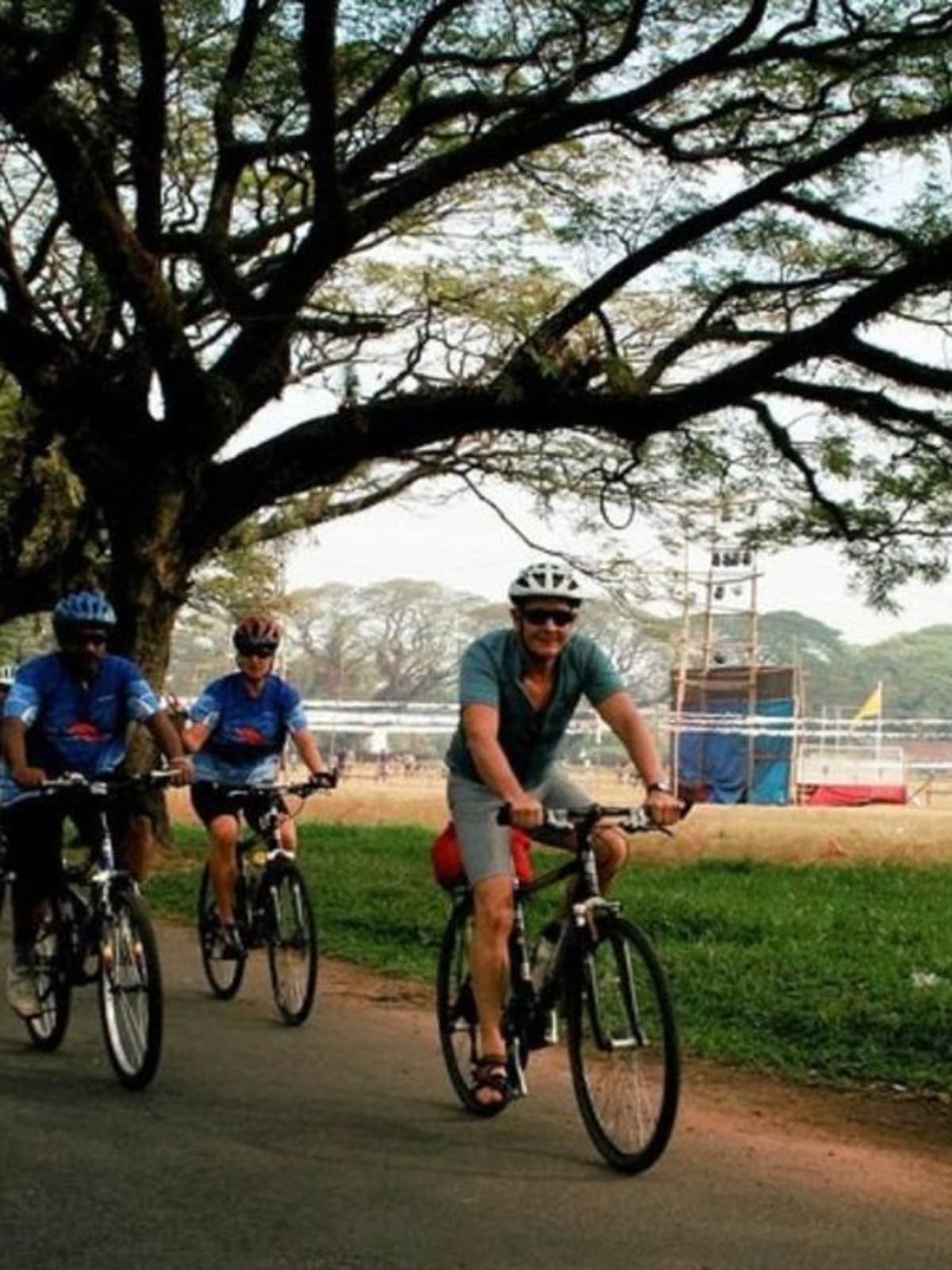 Cyclists riding on dedicated bicycle lane along tree-lined urban corridor in Indian city
