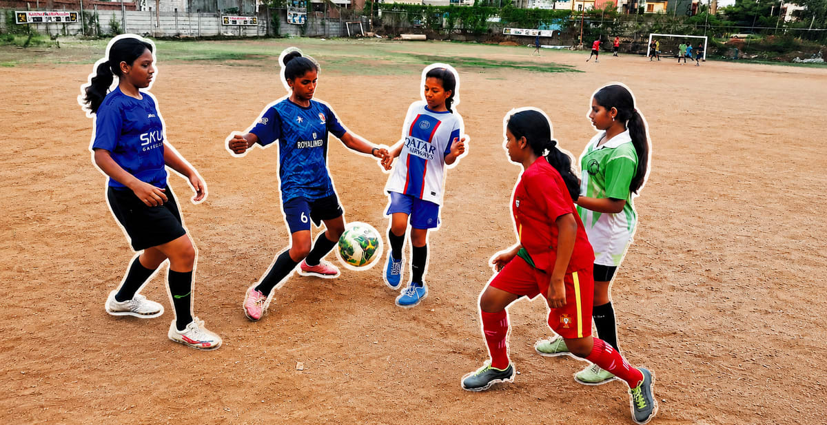 Young girls in sports uniforms playing football alongside boys on community ground in Telangana India