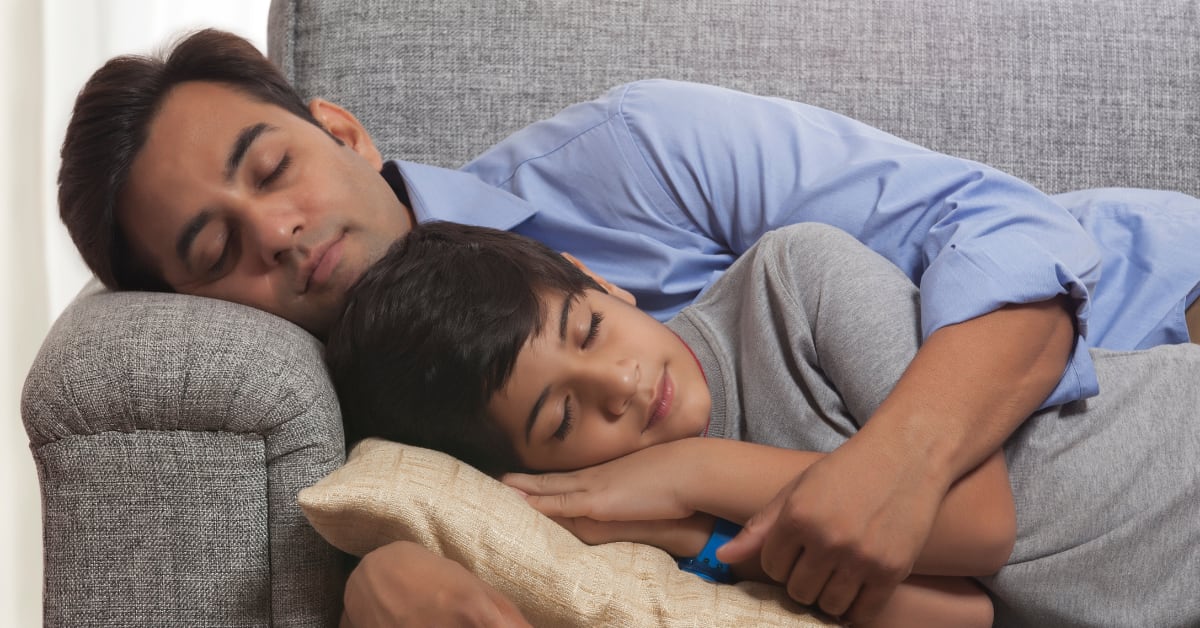 Indian mother and child sleeping peacefully together in warm family bedroom setting