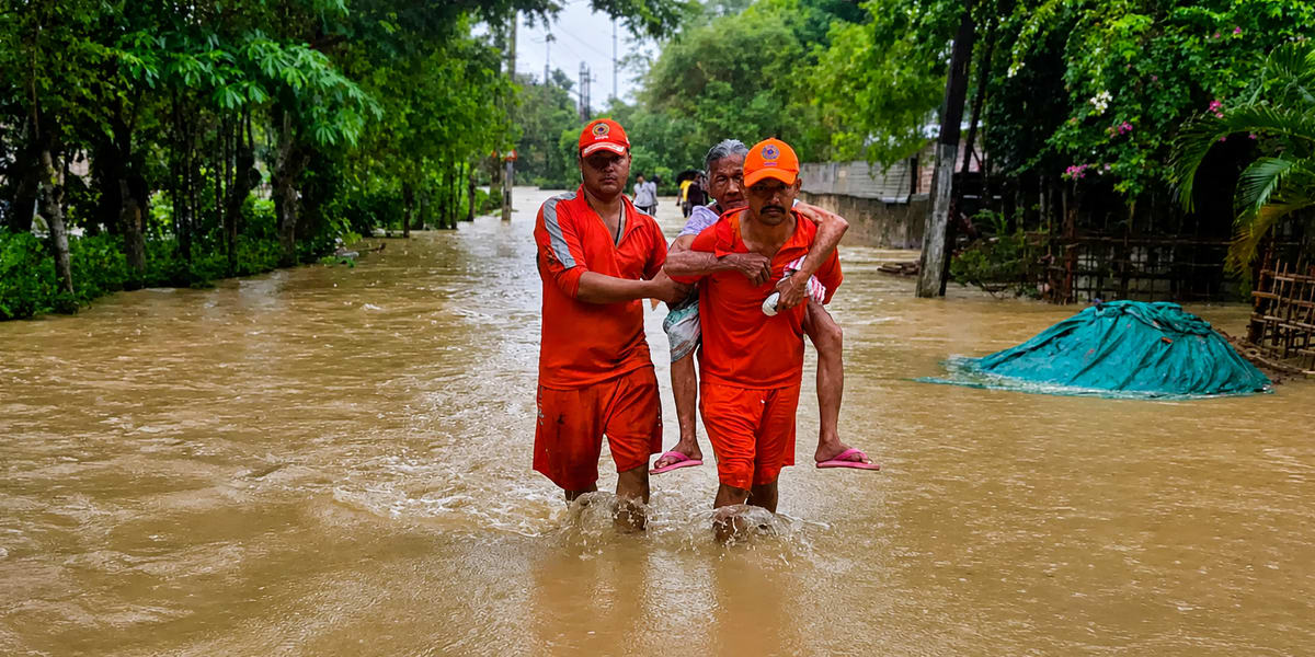 Rescue workers navigating boat through flooded village waters in Assam, India during monsoon