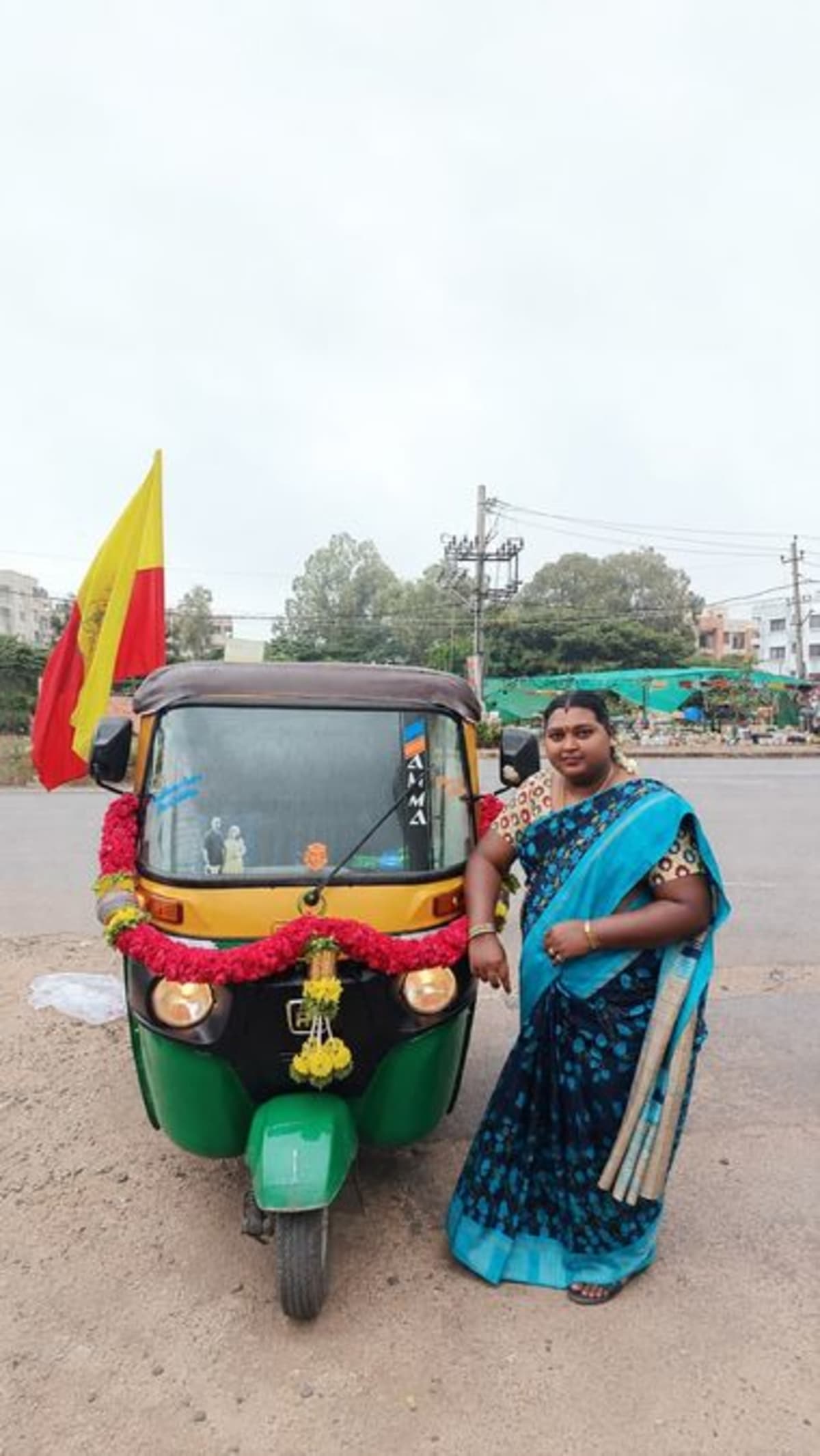 Indian woman teaching another woman to drive an auto-rickshaw on city street