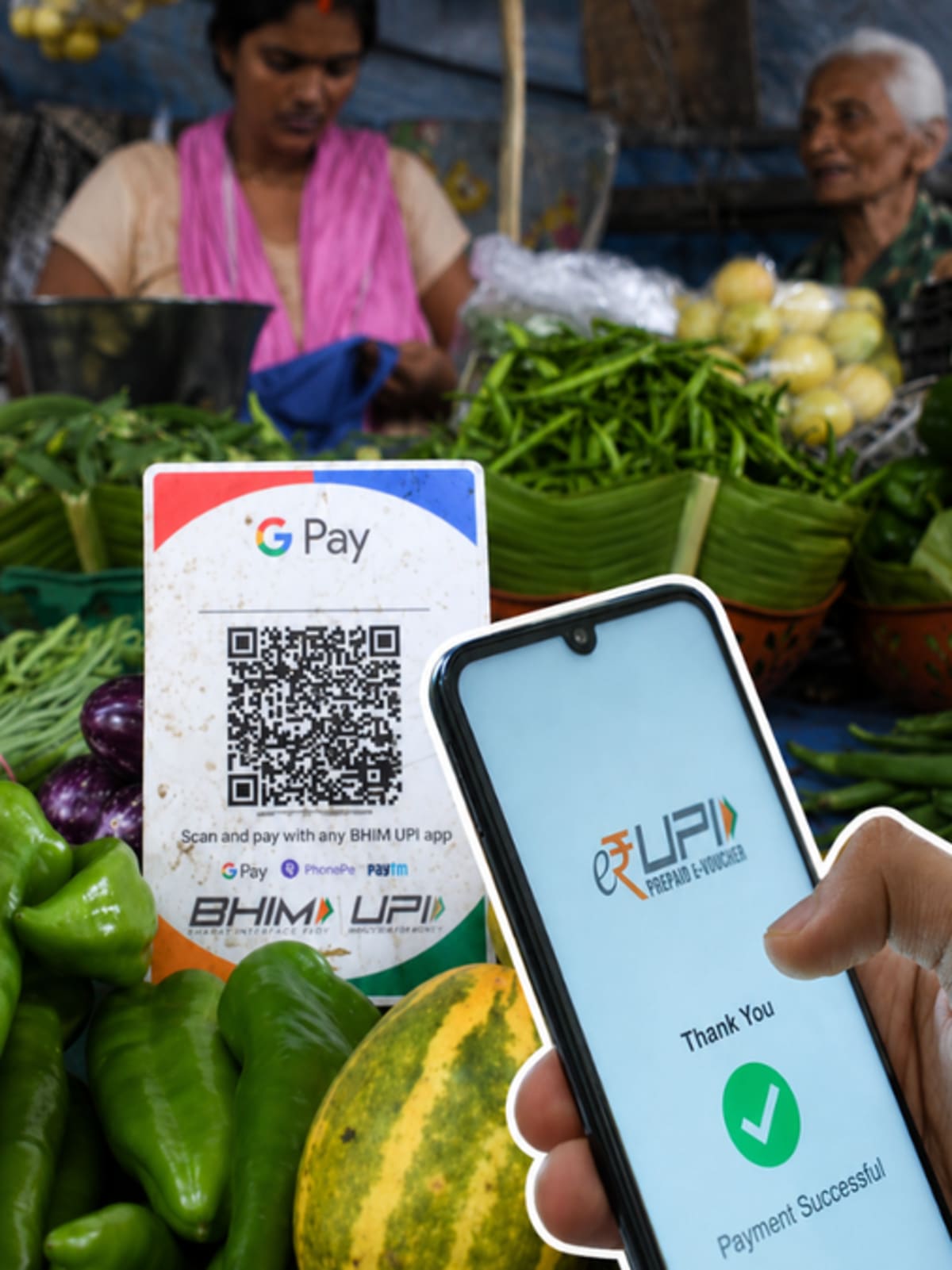 Indian merchant holding smartphone displaying UPI QR code payment scanner at small shop