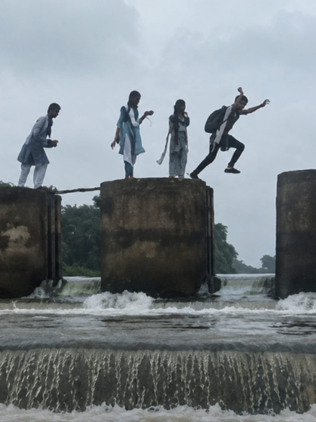 Children safely crossing a footbridge over a river on their way to school in rural India
