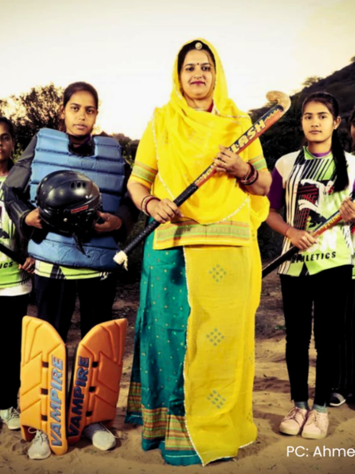 Young girls in sports uniforms holding hockey sticks in rural Rajasthan village