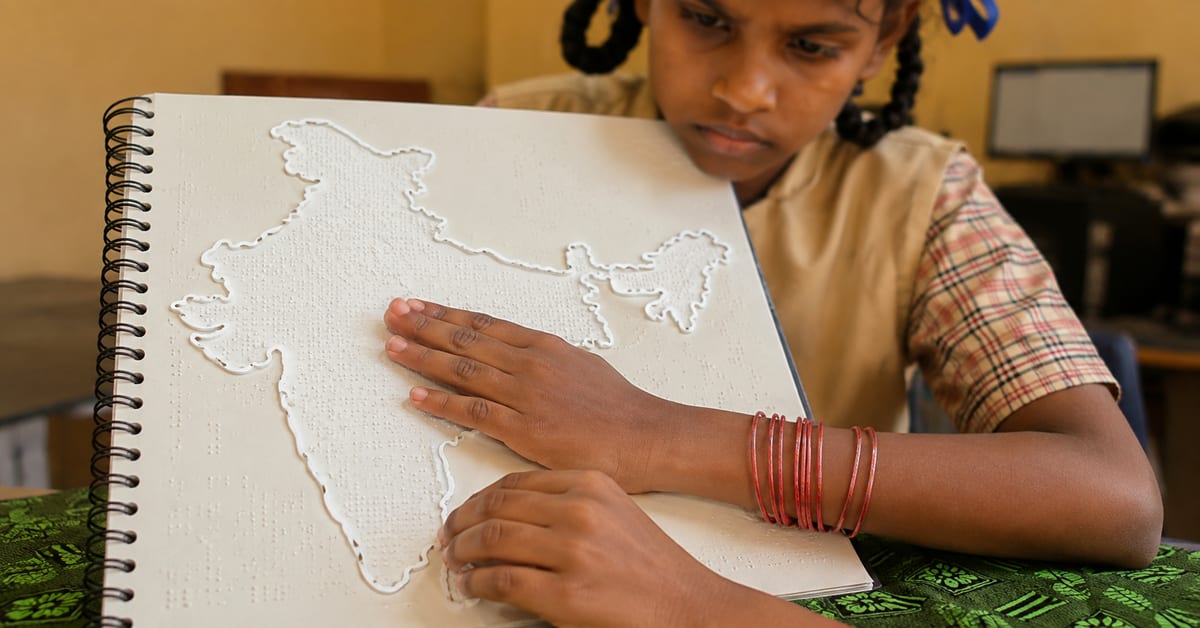 Designer Prabhu holding raised tactile map of India with visually impaired students