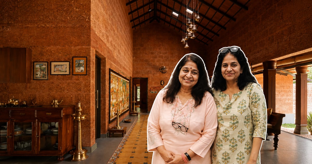 Terracotta-roofed Kerala home nestled among coconut palms and jackfruit trees with paddy fields beyond
