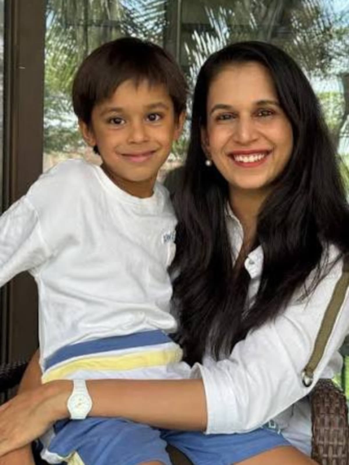 Mother greeting young child with warm hug after school at home entrance