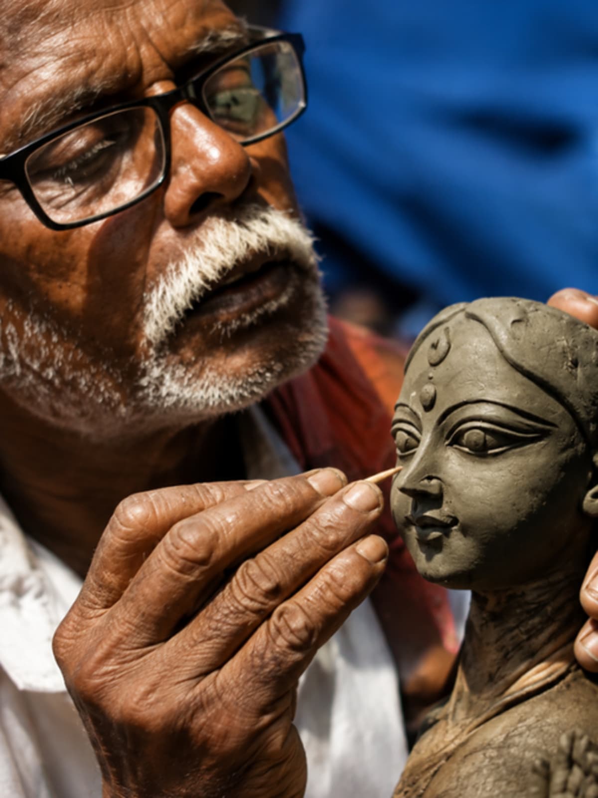 Artisan carefully painting detailed features on traditional Durga idol in Kumartuli workshop Kolkata