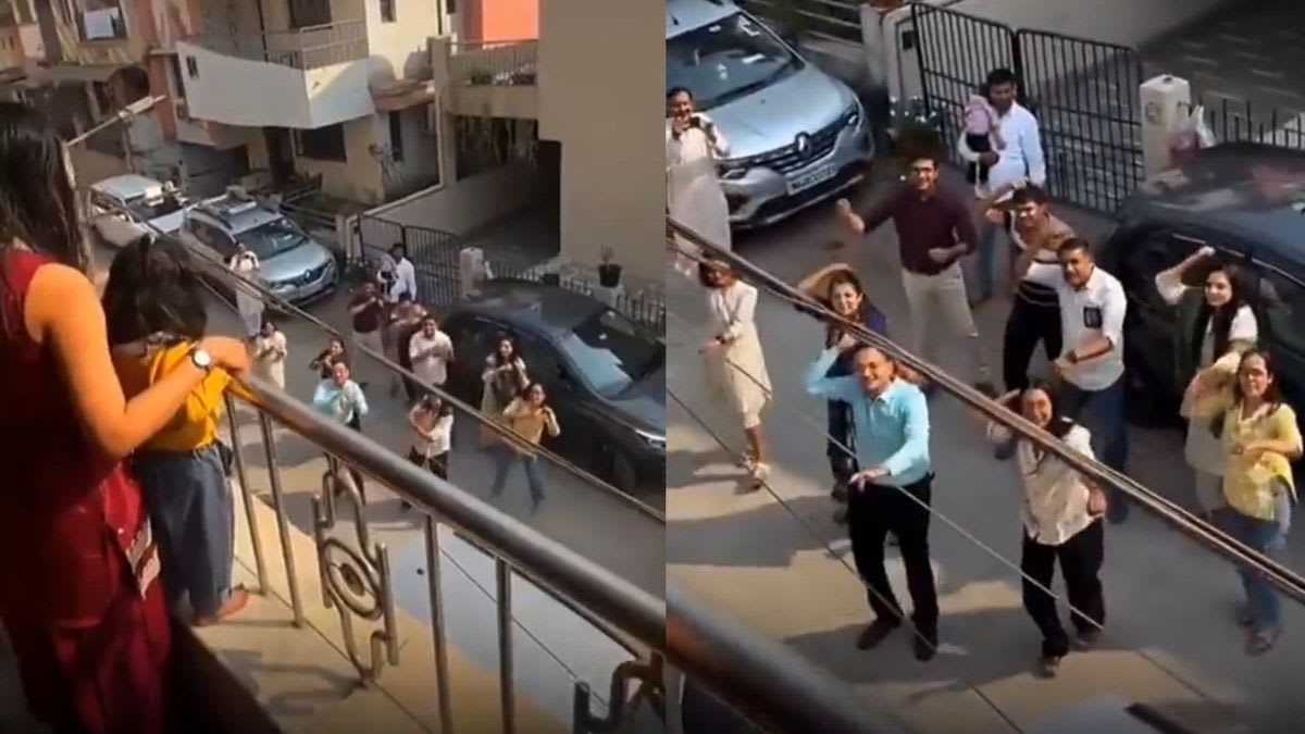 Family dancing together on street below balcony during musical marriage proposal