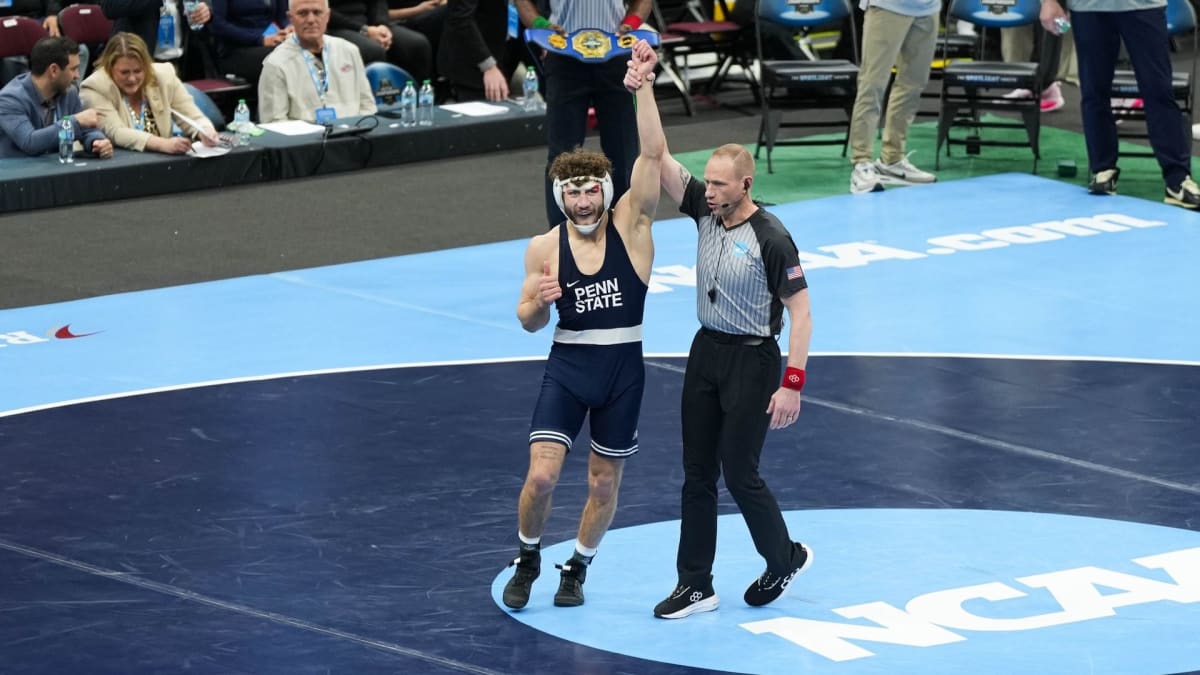 Penn State wrestlers celebrating fifth consecutive NCAA championship victory with trophy and medals