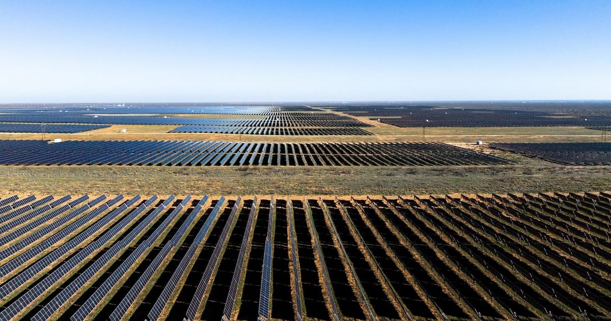** Rows of blue solar panels stretching across open Texas landscape under bright sunny sky
