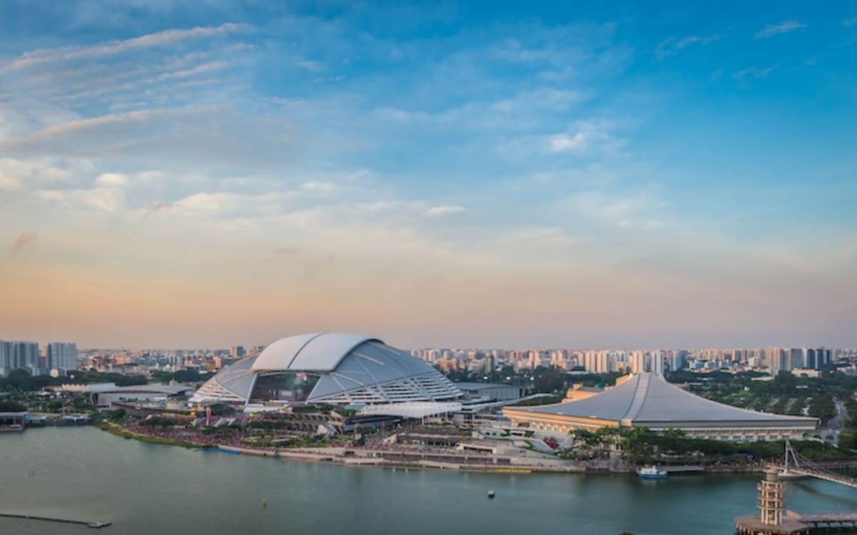 People walking together at Singapore's National Stadium with red lights illuminating the iconic venue