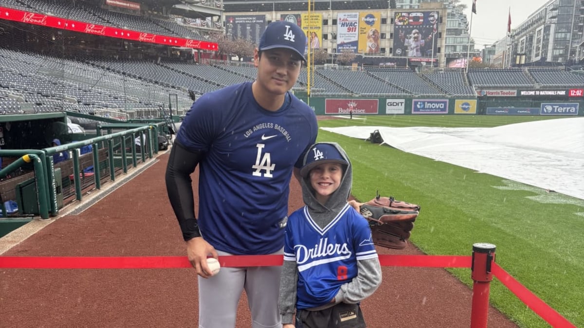Eight-year-old Kane Cochrane smiling with Shohei Ohtani in the rain at baseball stadium