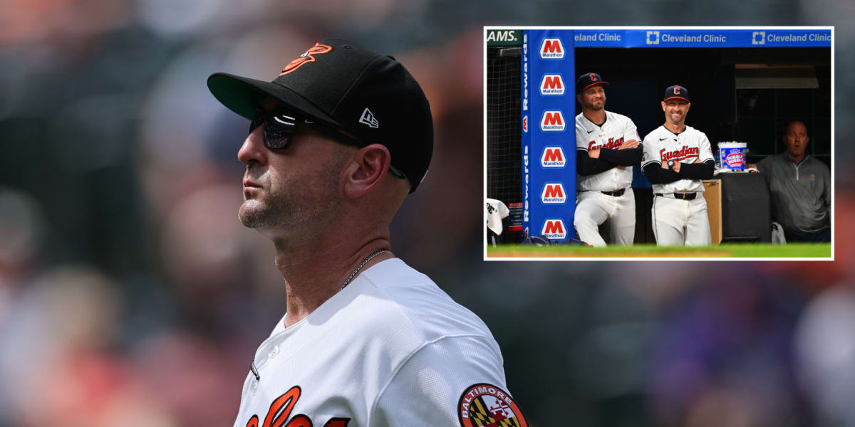Two baseball managers in dugouts smiling across the field at each other during game