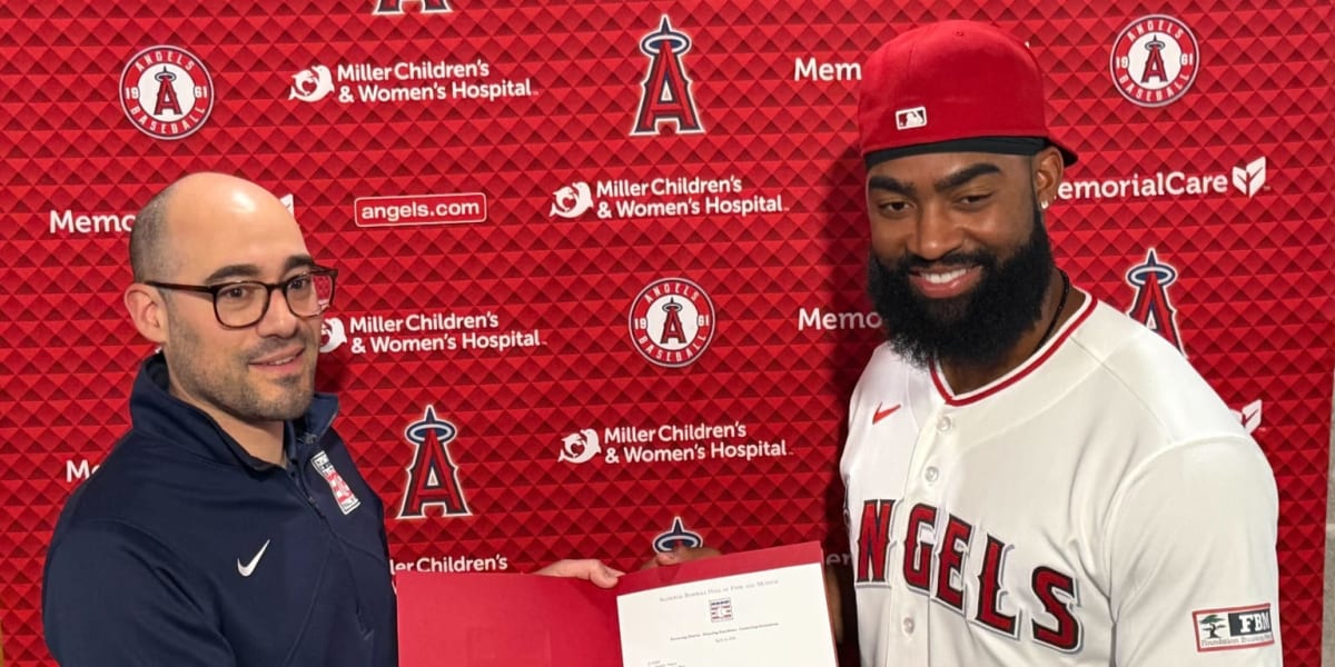 Jo Adell holding black Wilson baseball glove with Hall of Fame representative at donation ceremony