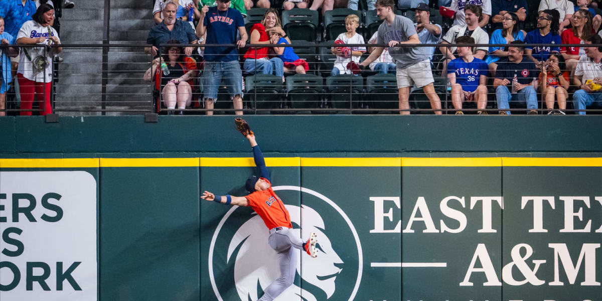 Houston Astros right fielder Cam Smith leaping above outfield wall to catch baseball