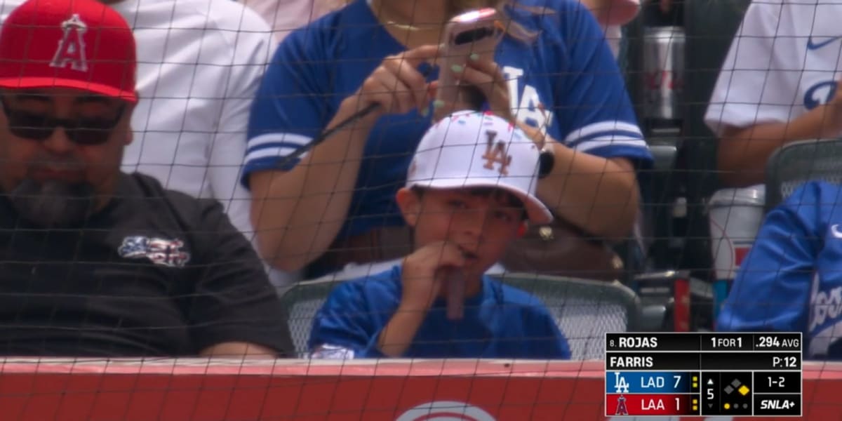 Young baseball fan cheering enthusiastically from front row seats behind home plate at stadium