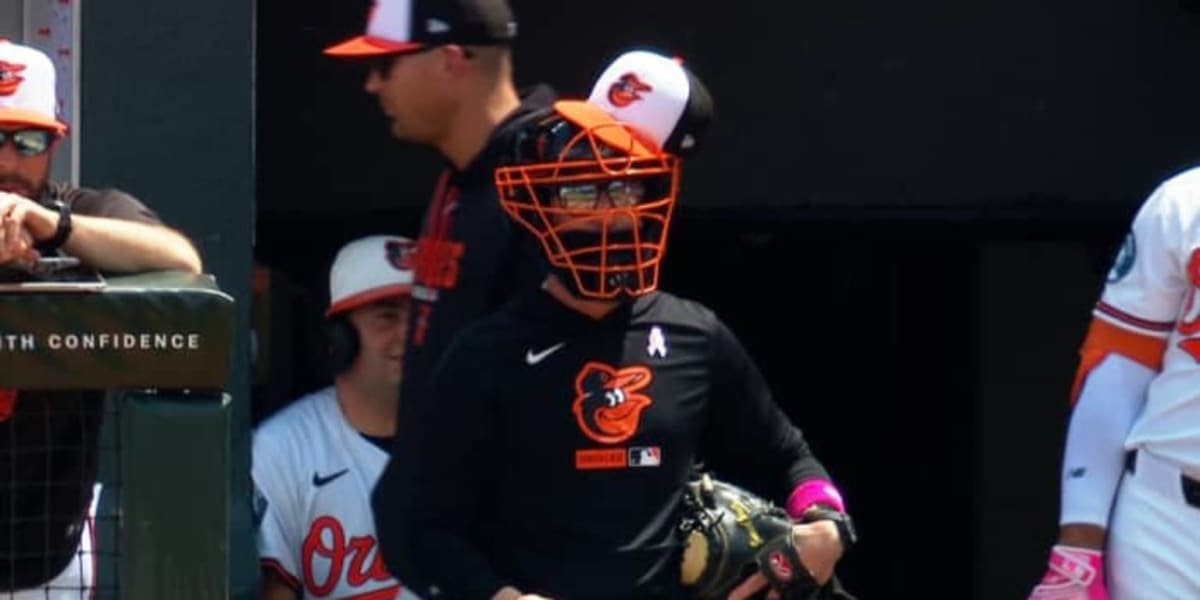 Orioles manager Craig Albernaz wearing catcher's mask and baseball cap in dugout