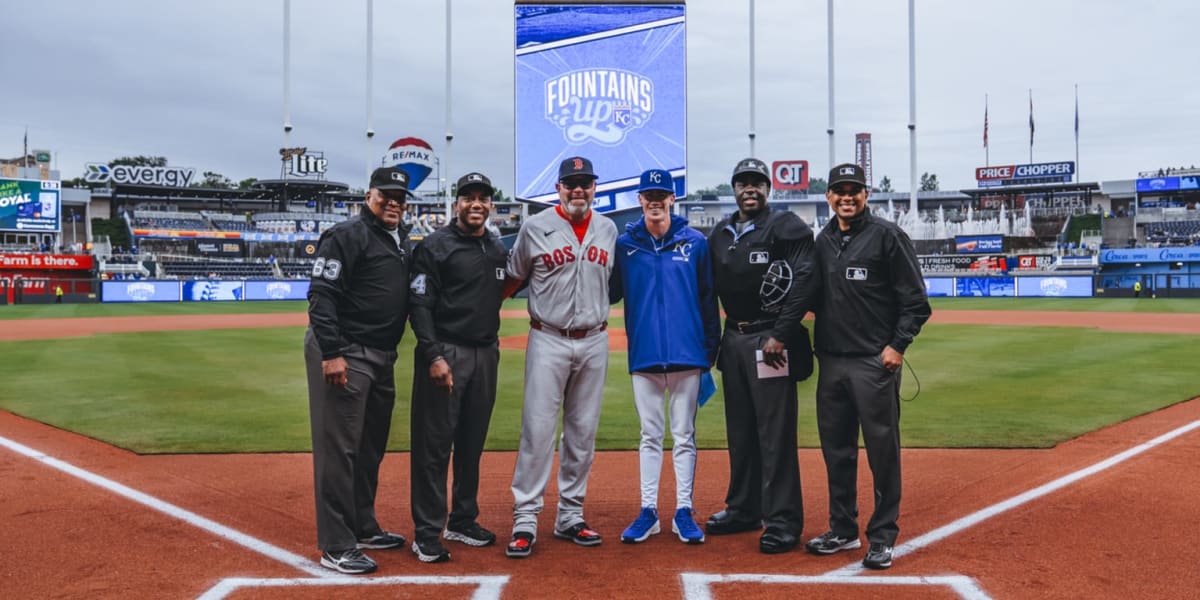 Father and son embrace at home plate in baseball uniforms during lineup card exchange