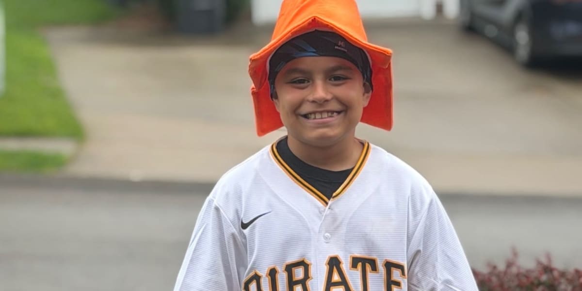 Young boy in Pirates baseball cap smiling at camera holding baseball glove